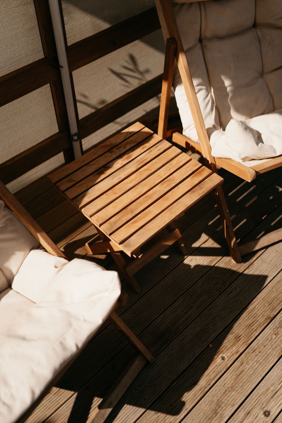 Chaises pliantes en bois et coussins écrus au soleil, ombres portées, photo d’ambiance