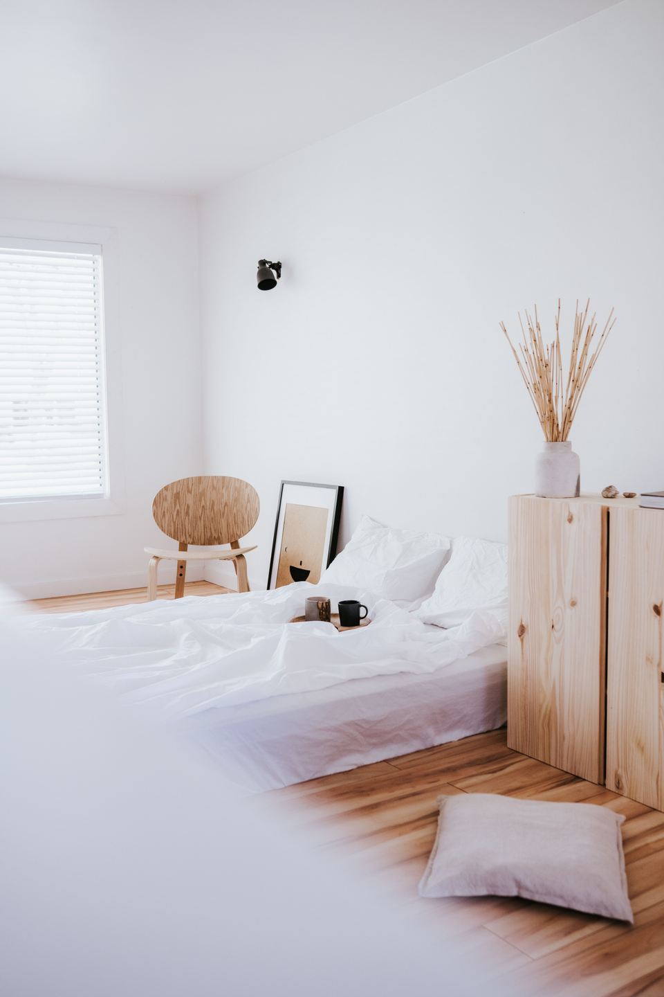 Chambre claire, lit de lin blanc, chaise en bois courbé et meuble de pin