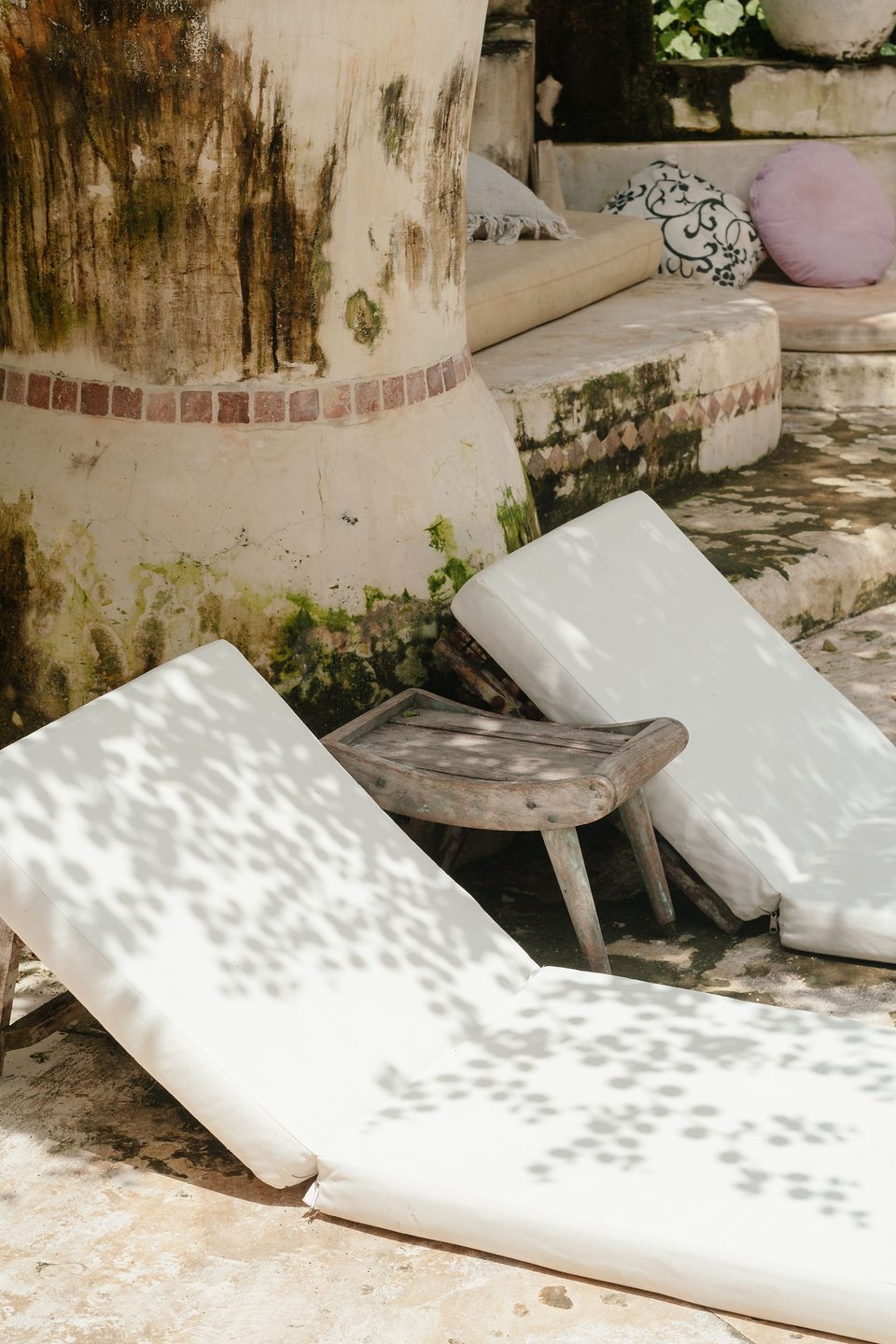 Matelas de bains de soleil blancs sous une ombre de feuillage