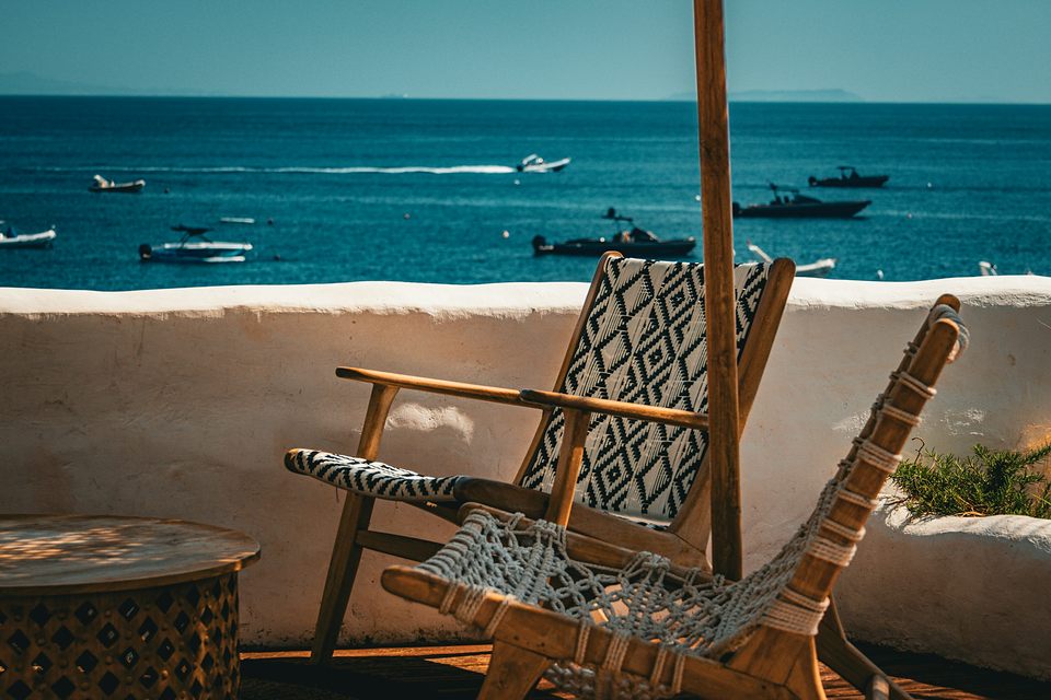 Fauteuils en bois tendus de toile tissée, terrasse à la chaux face à la mer