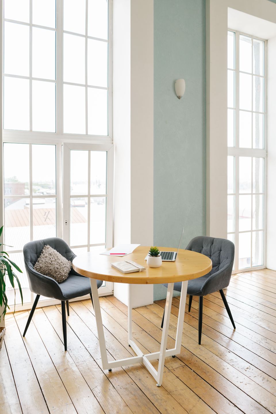 Bureau clair aux hautes fenêtres, table ronde et fauteuils tapissés gris