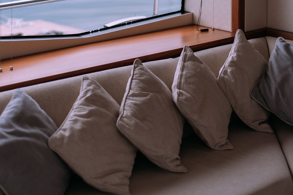 Coussins alignés sur une banquette, sous un hublot