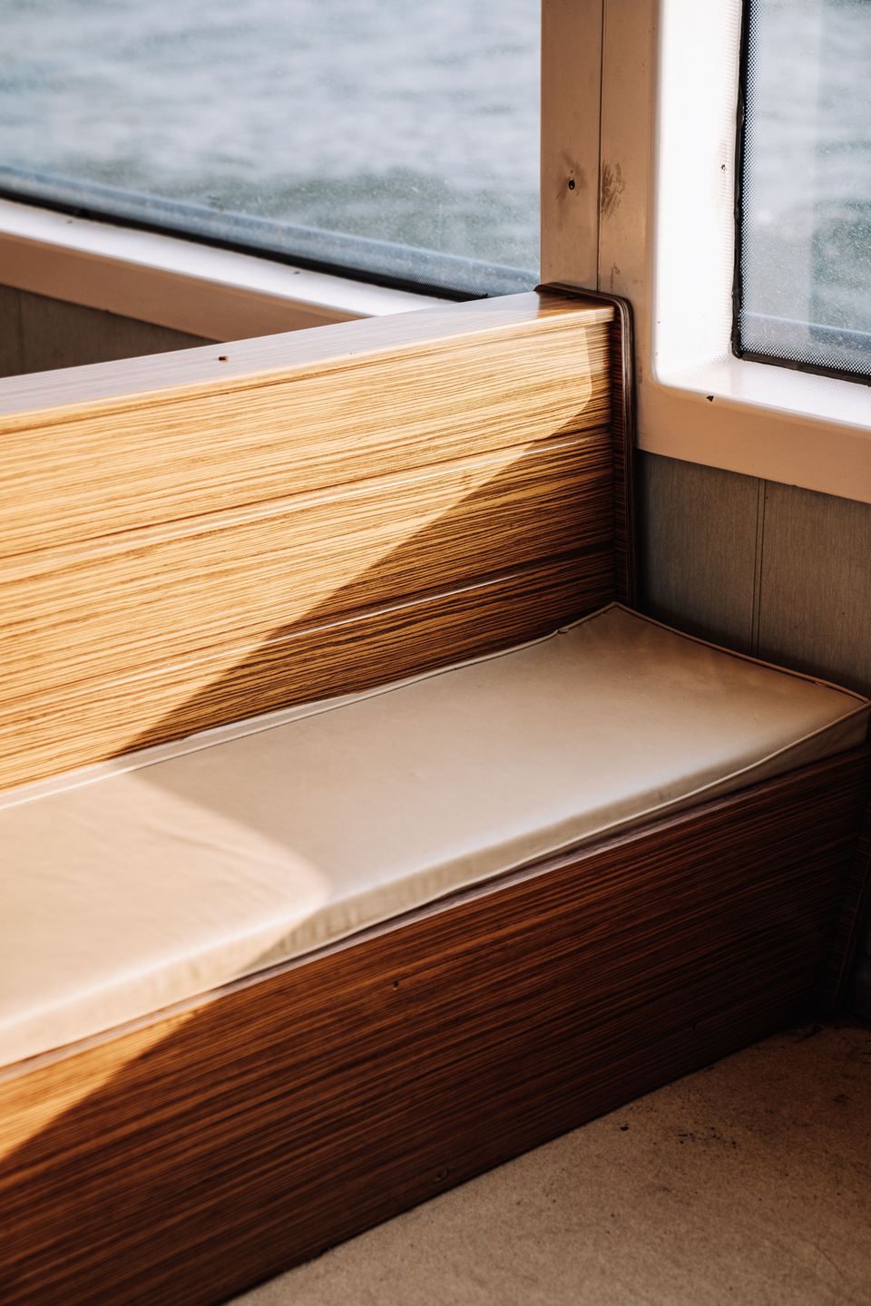 Banquette de bord en bois et coussin clair sous une fenêtre