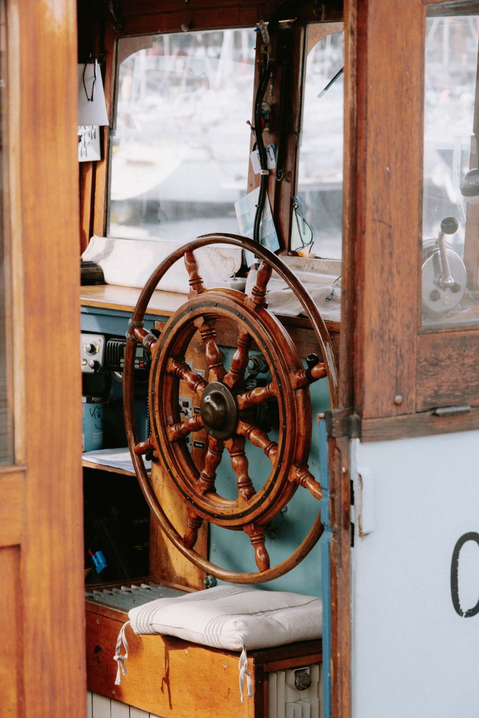 Barre à roue en bois et coussin blanc dans la timonerie d’un voilier ancien
