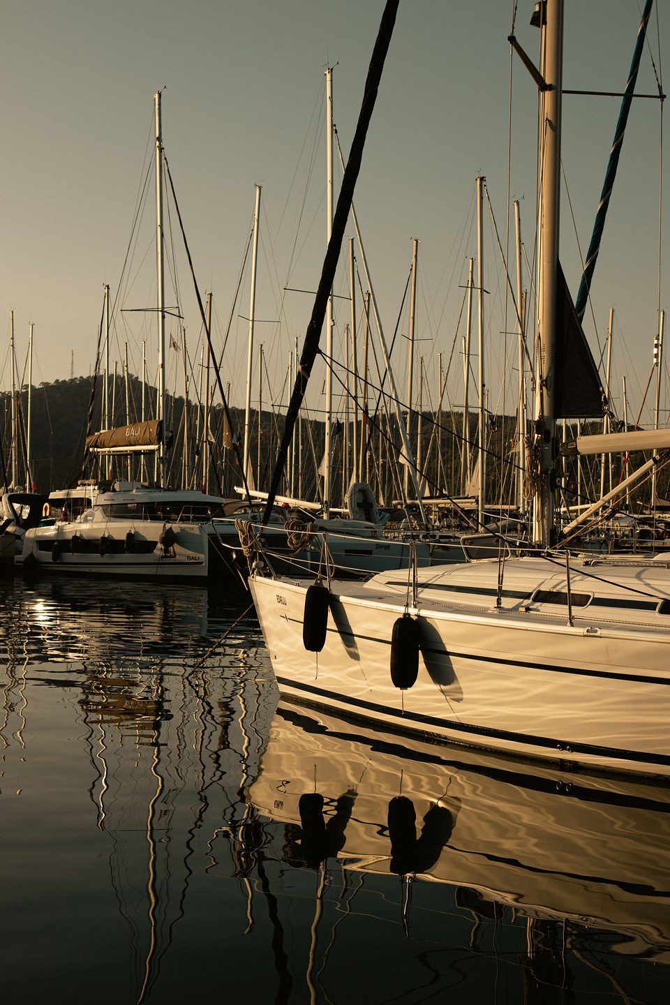 Voiliers amarrés dans un port, lumière dorée du soir