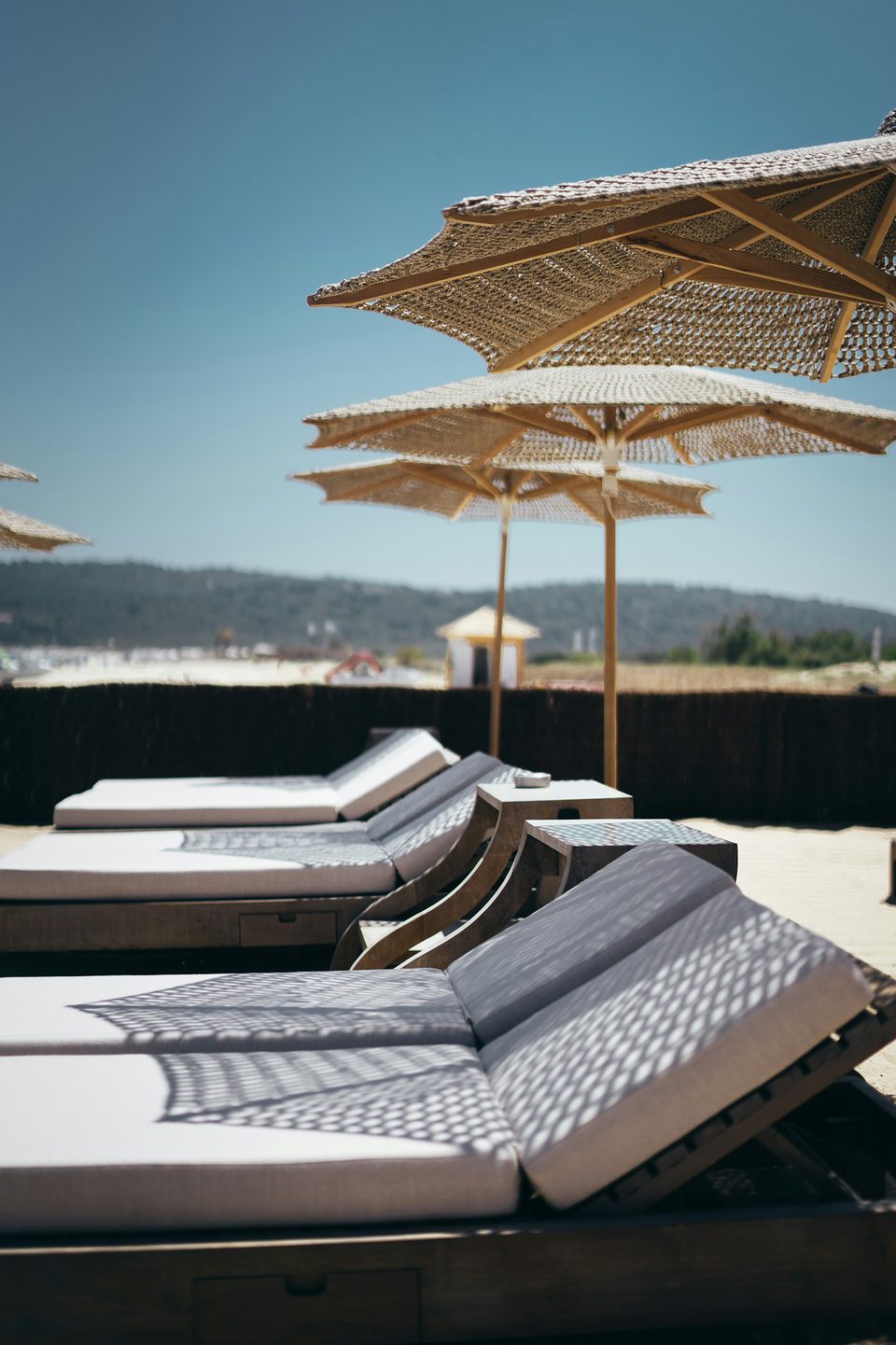 Bains de soleil sous des parasols tressés, la mer au loin